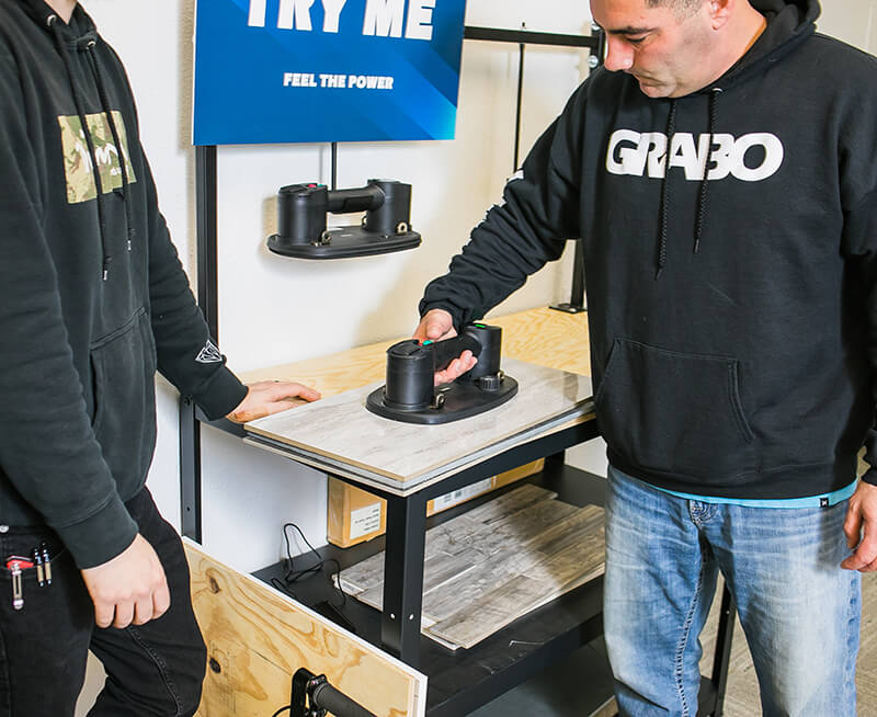 A demonstration stand with a man using a grabo to lift some material
