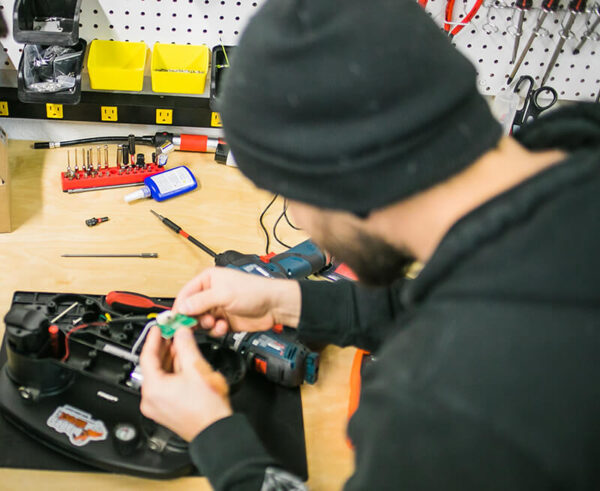 A man at a workshop desk fixing a grabo